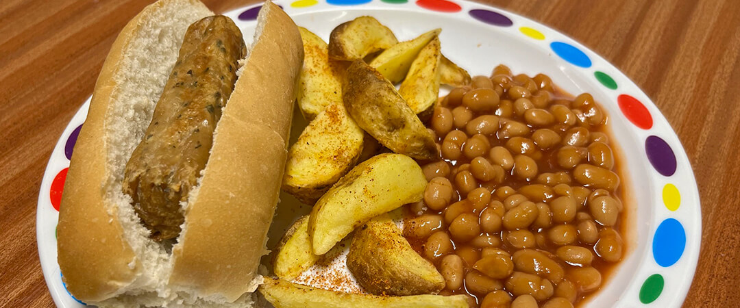 Quorn sausage hotdog (Ve) served with BBQ wedges and baked beans