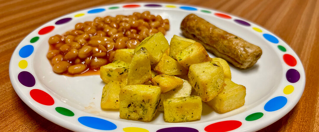 Vegetarian sausage (Ve) served with herby diced potatoes, baked beans or peas and bread and spread