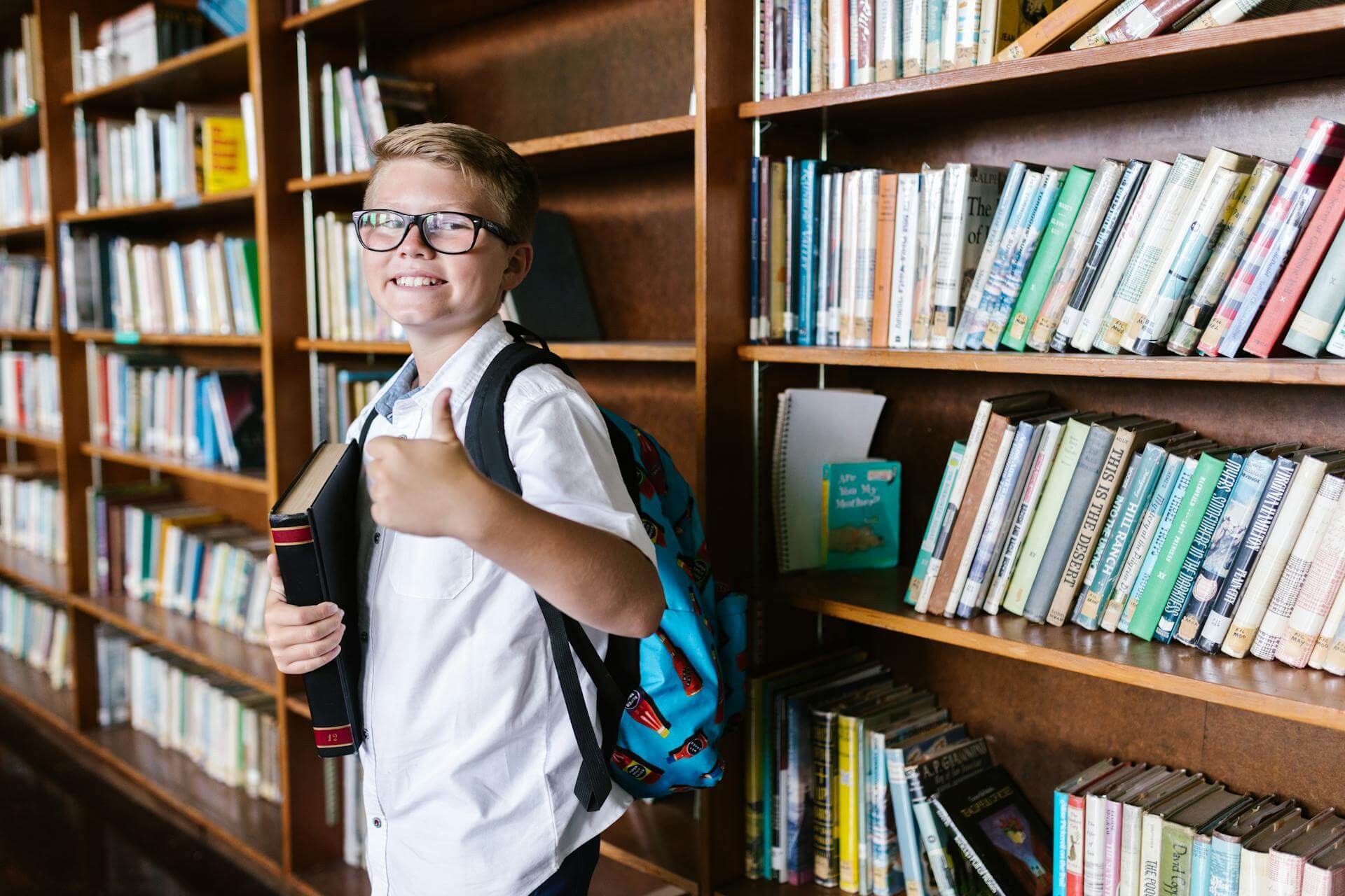 A boy in the library with his thumbs up (Pexles - RDNE Stock project)