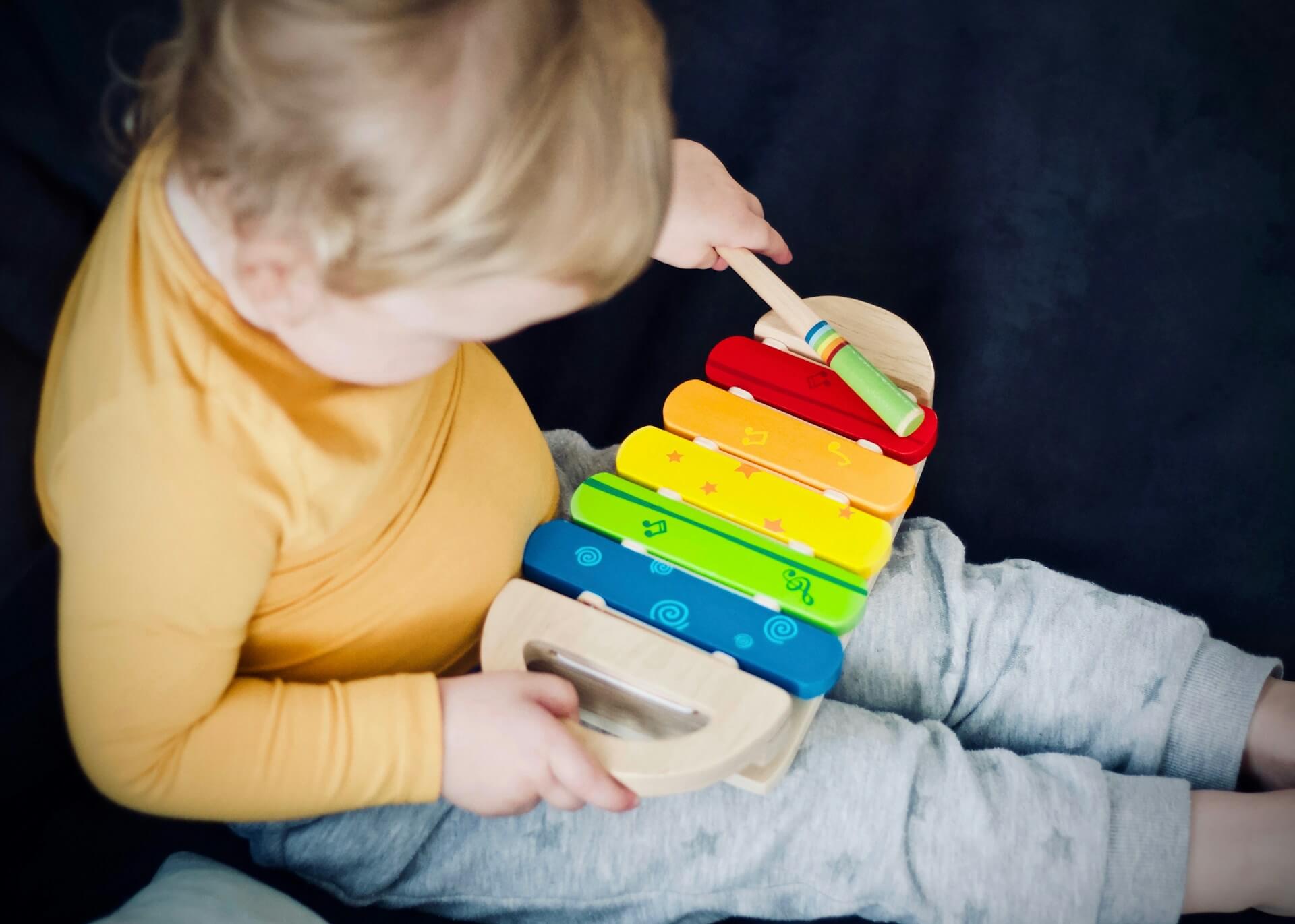 Child playing with colourful toy xylophone (Unsplash - Jelleke Vanooteghem)
      