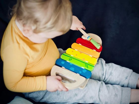 Child playing with colourful toy xylophone (Unsplash - Jelleke Vanooteghem)