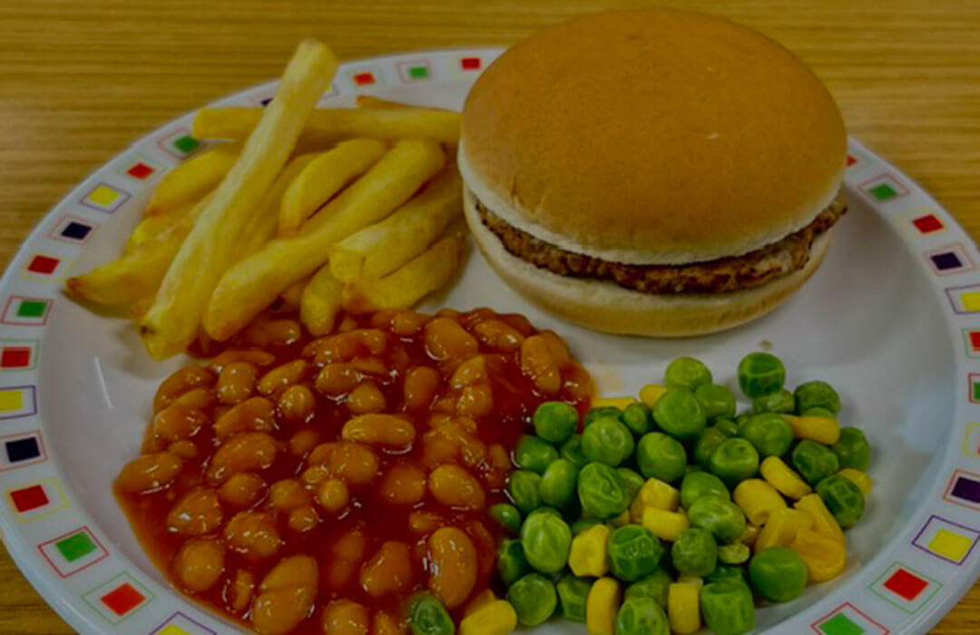 Beefburger in a roll or bread and spread served with chips, peas and sweetcorn or baked beans