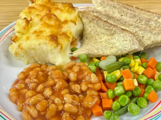 Cheese and potato pie served with mixed vegetables, broccoli, gravy and bread and spread