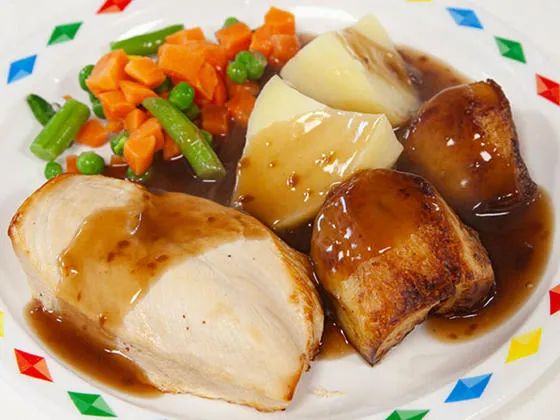 Chicken breast fillet served with stuffing, roast and boiled potatoes, vegetables and gravy