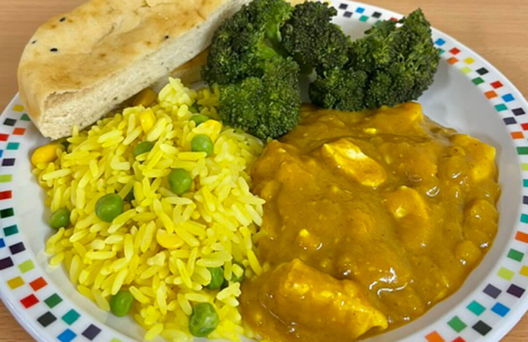 Homemade chicken curry served with savoury vegetable rice, broccoli and Naan bread