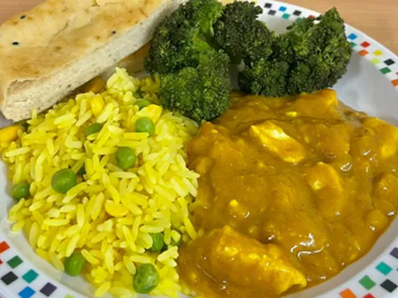 Homemade chicken curry served with savoury vegetable rice, broccoli and Naan bread