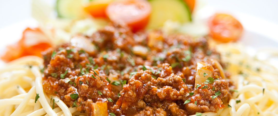 Pasta bolognese served with garlic bread and side salad