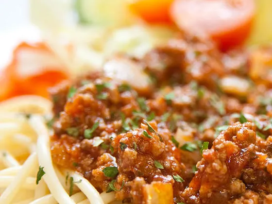 Pasta bolognese served with garlic bread and side salad