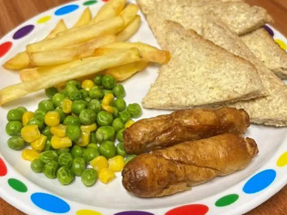 Quorn sausage (Ve) in a roll or bread and spread served with chips, peas and sweetcorn or baked beans