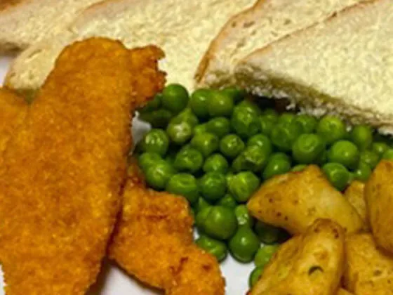 Chicken goujons served with herby diced potatoes, peas, bread and spread