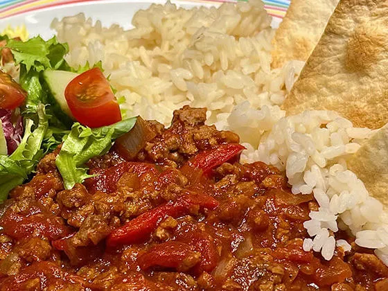 Homemade BBQ beef served with rice, tortilla chips and salad