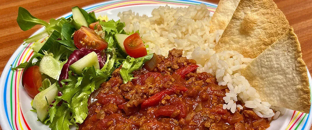 Homemade BBQ beef served with rice, tortilla chips and salad