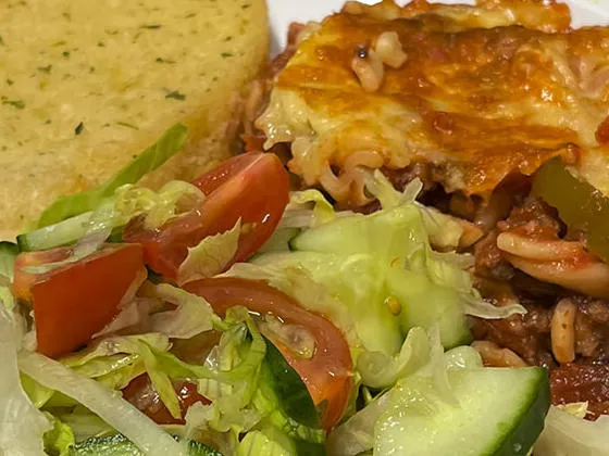 Homemade bolognese pasta bake served with garlic bread and salad