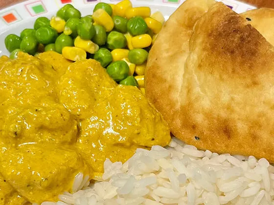 Homemade chicken curry served with rice, peas, sweetcorn and Naan bread