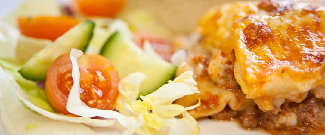 Homemade lasagne served with garlic bread and salad
