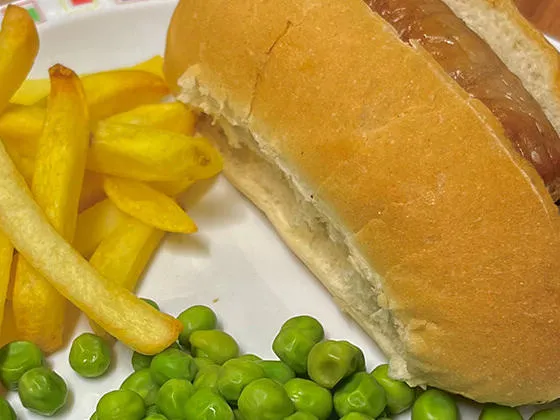 Hotdog served with chips and peas