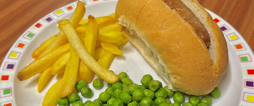 Hotdog served with chips and peas