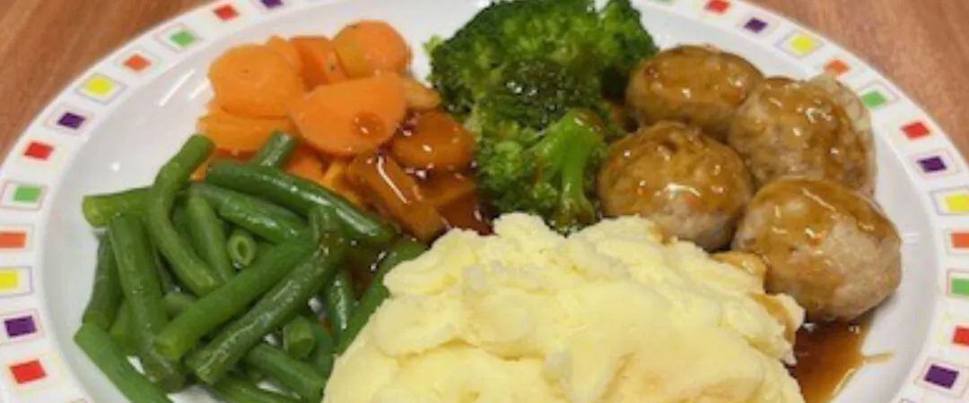 Pork and carrot meatballs in gravy served with mashed potato, broccoli, carrots, green beans and gravy