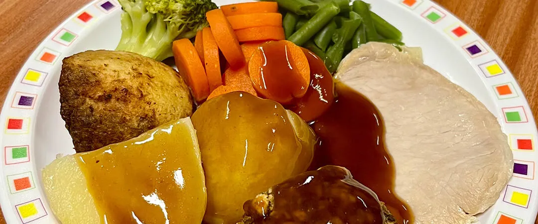 Pork loin served with roast and boiled potatoes, veg selection and gravy