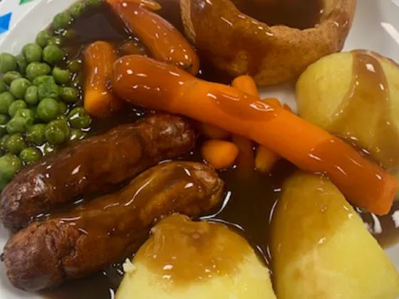 Pork sausage served with yorkshire pudding, roast and boiled potatoes, veg selection and gravy