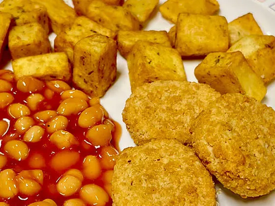 Vegetable nuggets (Ve) served with herby diced potatoes and baked beans
