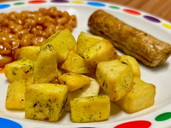 Vegetarian sausage (Ve) served with herby diced potatoes, baked beans or peas and bread and spread
