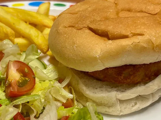 Veggie burger in a bun served with chips and peas