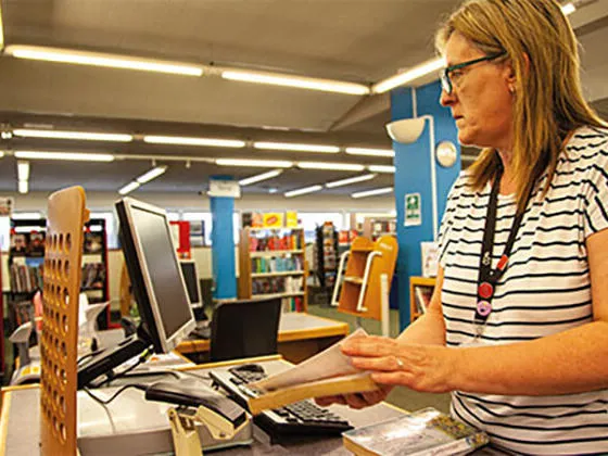 A member of staff working in a library scanning books