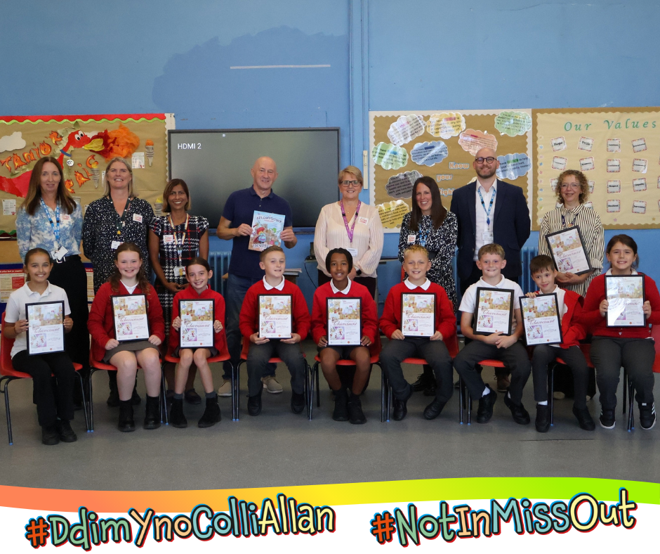 A group of New Inn Primary School pupils holding up copies of the books front cover artwork, alongside staff.